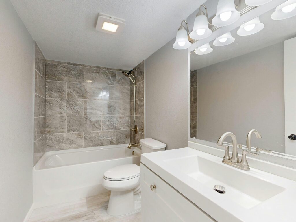 Elegant modern bathroom featuring marble tiles and sleek white vanity.