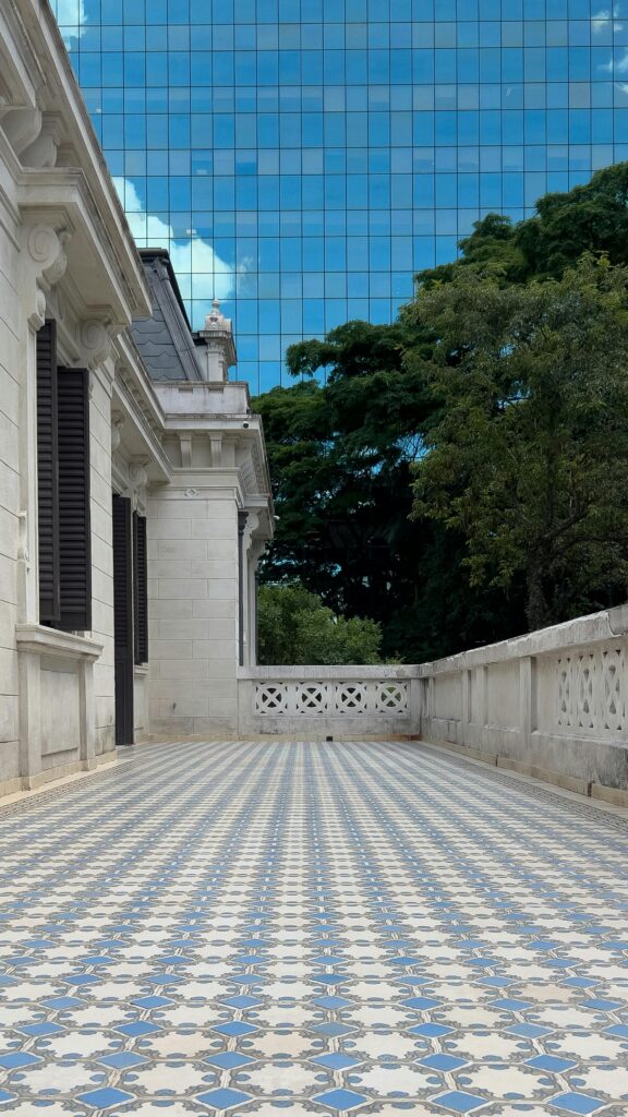 Spacious terrace with elegant blue mosaic tiles and classic architecture in SP, Brazil, against a cityscape and sky backdrop.